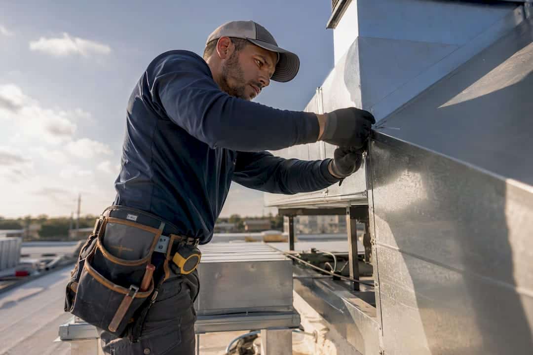 Technician installing HVAC unit on commercial building rooftop.