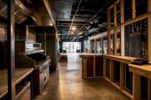 Modern commercial kitchen under renovation with stainless steel appliances and wooden framing.