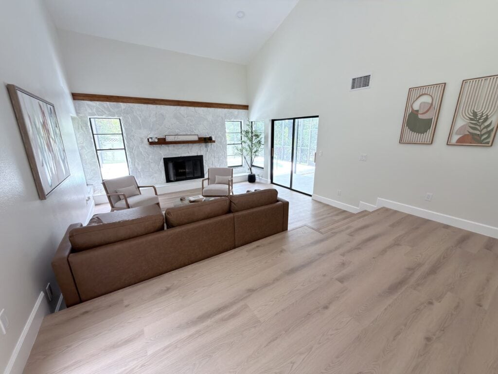 LVP flooring Tampa: plank floor running wall to wall through a living room with a fireplace