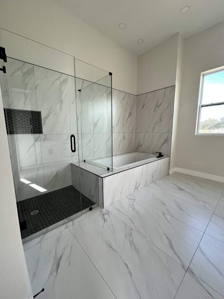 Tile installation Tampa: tiled walk in shower with a glass panel and a pebble shower floor